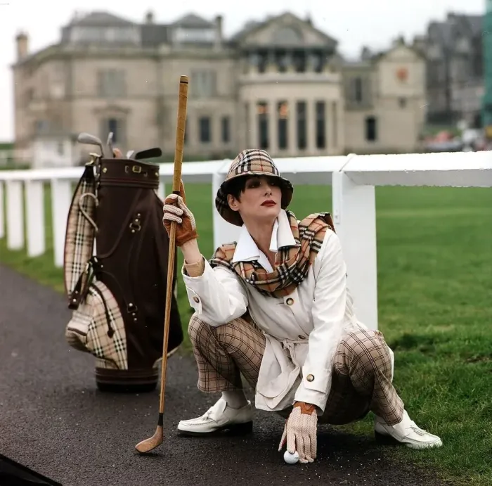 Framed Print : Golf Fashion woman crouching down next to golf bag clubs Burberry type checked hat Framed Print : Golf Fashion woman crouching down next to golf bag clubs Burberry type checked hat