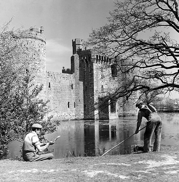 A groundkeeper cleaning the moat outside Bodiam Castle, a 14th-century moated castle near