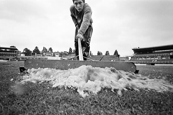 Groundsman Ian Guys tries to clear the water from the pitch at Edgbaston ahead of