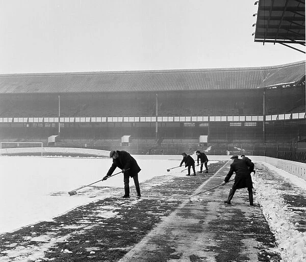 Groundsmen try to clear the snow from the pitch at Goodison Park