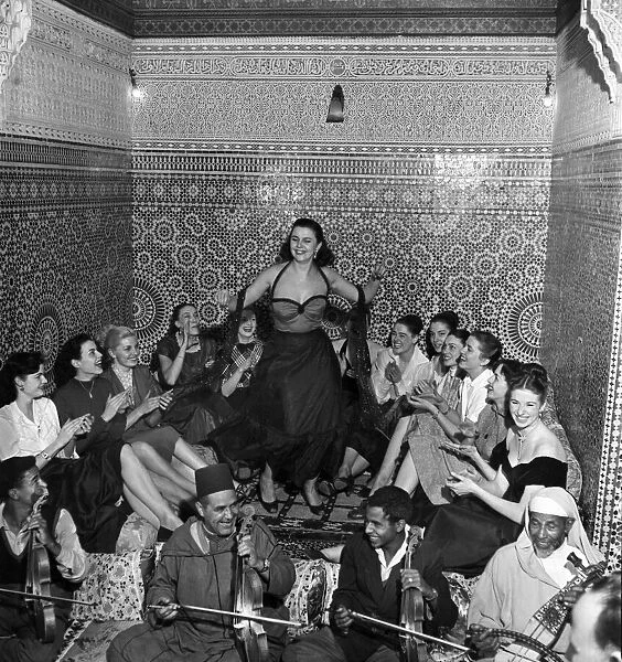 A group of French actresses enjoy a performance by a local belly dancer during a night