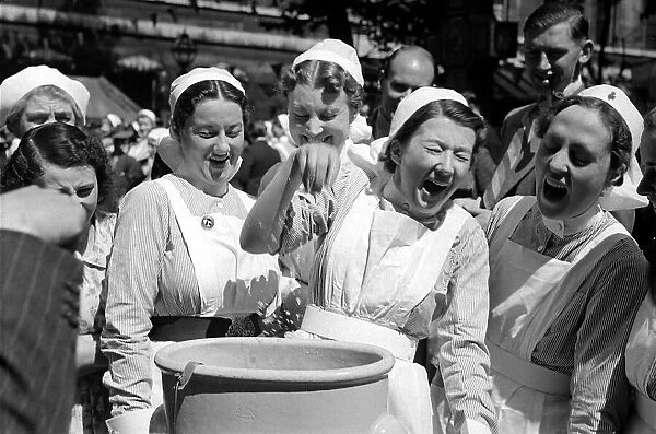A group of nurses laugh as one has to dunk her hand into a bucket at Barts Fair