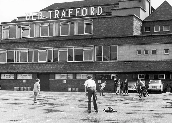 A group of young lads play a game of cricket outside Old Trafford ground
