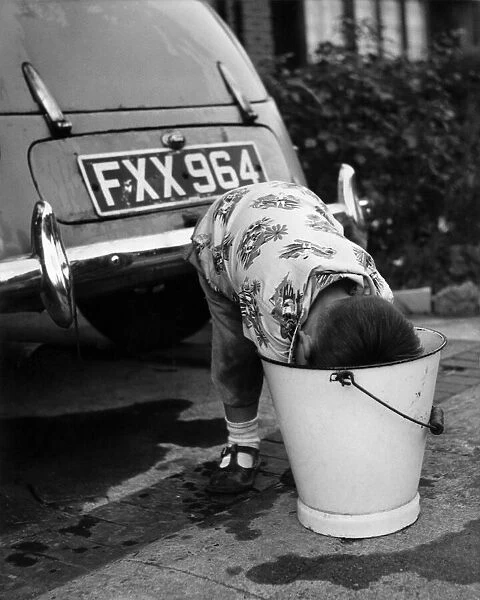 A three and a half year old boy washing fathers car