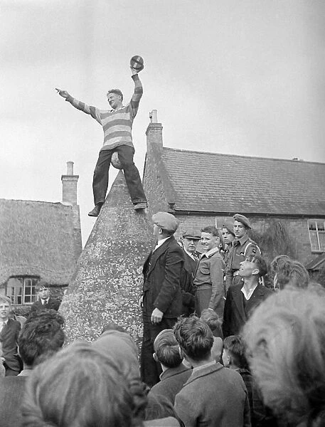 Hallaton Barrel Kicking man perched atop of a stone structure circa 1946