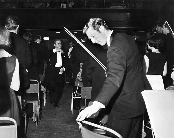 The Halle Orchestra stand to Sir John Barbirolli as he leaves the stage of the Free Trade