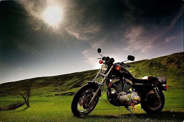 Harley Davidson motorbike sitting in field June 1998 sun shining dark skies