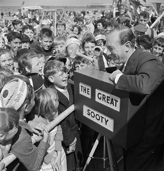 Harry Corbett and Sooty mobbed by fans at the Daily Mirror Beach party. August 1958