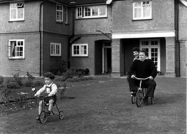 Harry Secombe at home, riding a bike in the garden circa 1970s