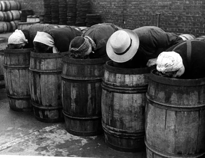 Framed Print : Hat fashions seen at Yarmouth as fisher girls bend over barrels whilst packing herring