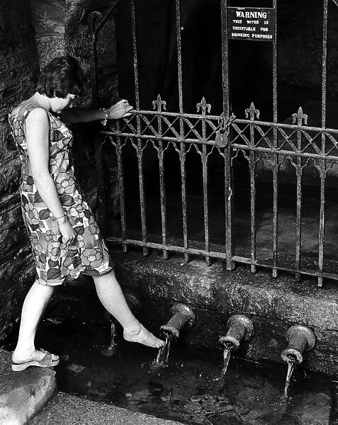 Heather Doney wets her foot at the pipe well in Well Lane at Liskeard, Cornwall