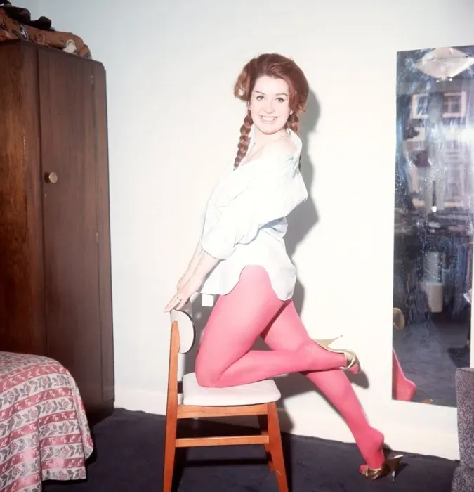 Framed Print : Heller Toren model actress 1964 knee on chair holding back pink tights white shirt