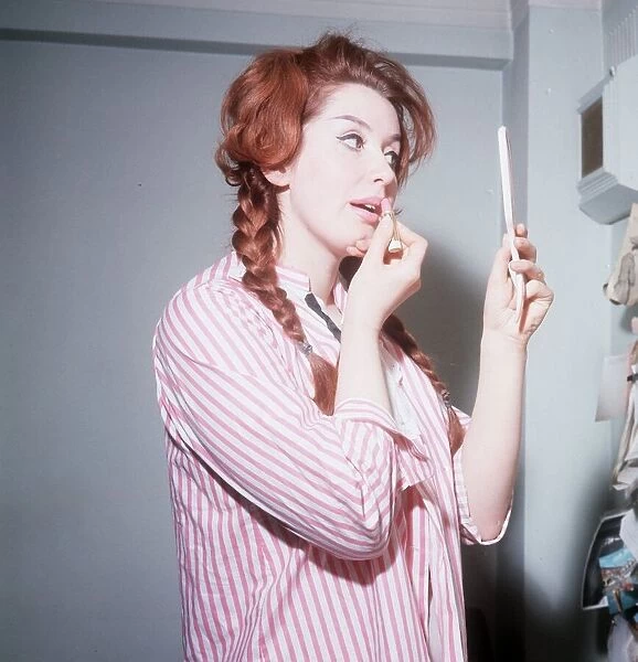 Heller Toren model actress 1964 puting on lipstick holding hand mirror pink striped shirt