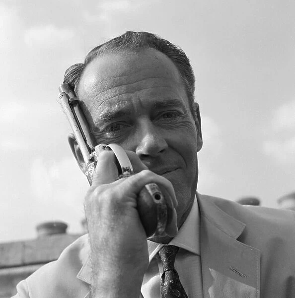 Henry Fonda on the roof of Television House, holding a revolver next to his face