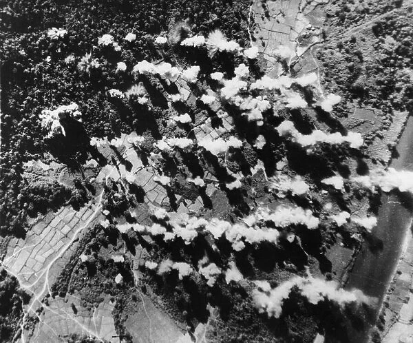 High explosive and sticks of 4 lb incendiary bombs explode on a Japanese supply dump in a