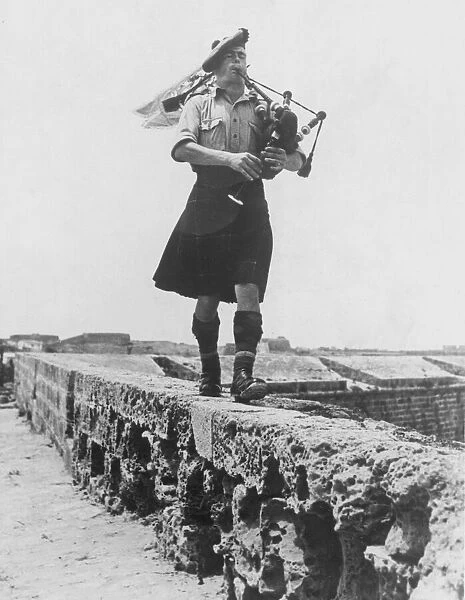 A Highland piper on duty one of the crusaders ancient battlements on the island of