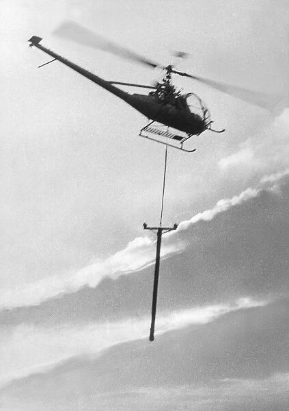 A Hiller 12E helicopter carries a telegraph pole across Grouse Moor at Kings Law