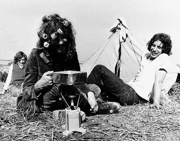 Hippies on Isle of Wight for pop festival cooking on camping stove in front of tent