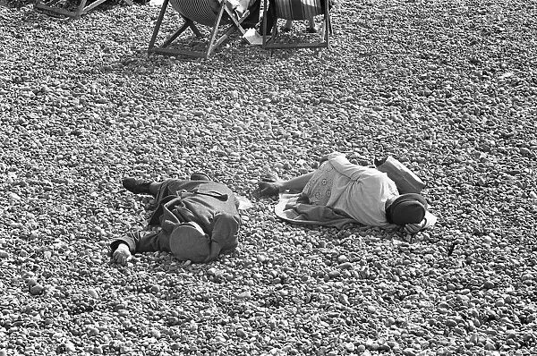 Holiday scenes at Brighton. Two elderly holidaymakers sleeping on the beach after