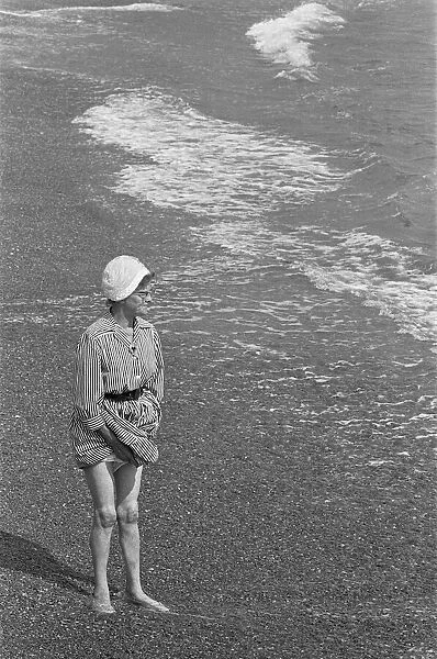 Holiday scenes at Brighton Elderly woman paddling in the sea holding her skirt up