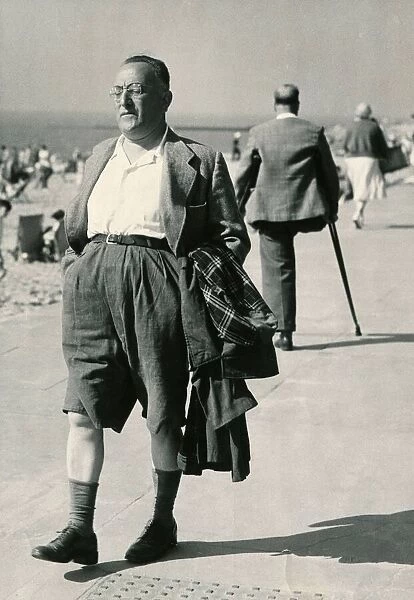 A holidaymaker with his raincoat under his arm strolls along the seafront at Clacton