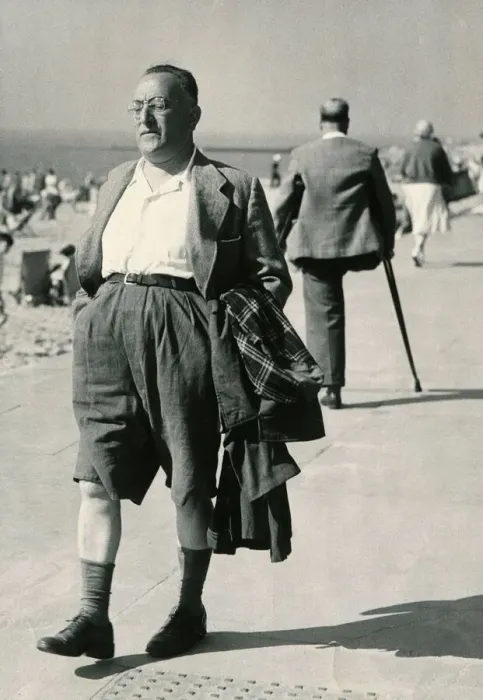 Framed Print : A holidaymaker with his raincoat under his arm strolls along the seafront at Clacton