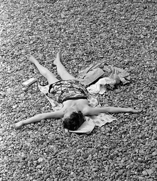 Holidaymaker sunbathing on the pebble beach at Brighton July 1958