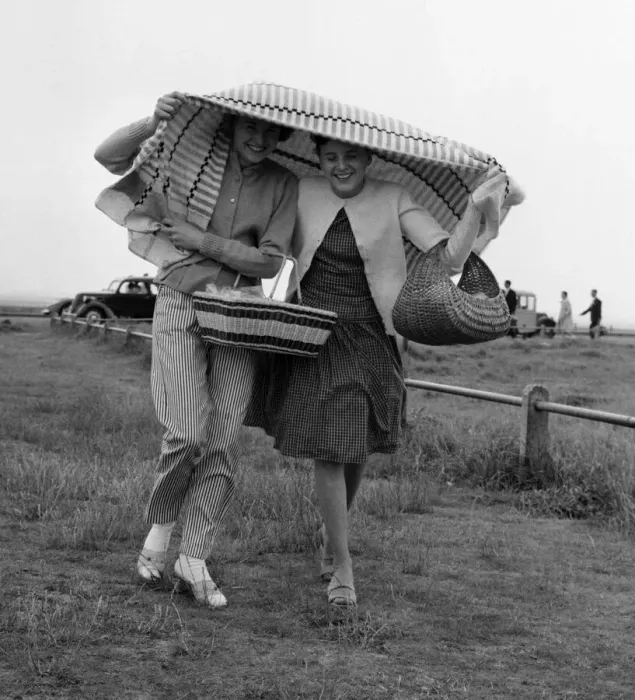 Framed Print : Holidaymakers covering their heads run for cover after being caught in a shower