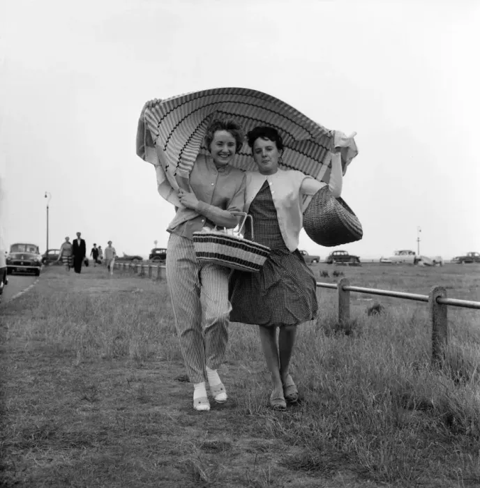 Framed Print : Holidaymakers covering their heads run for cover after being caught in a shower