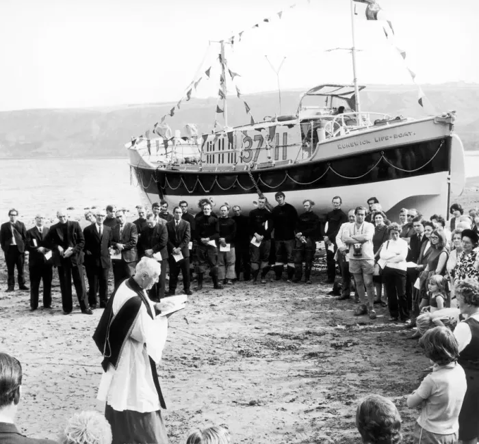 Framed Print : Holidaymakers and local residents join a seashore service to rededicate Runswick Bay