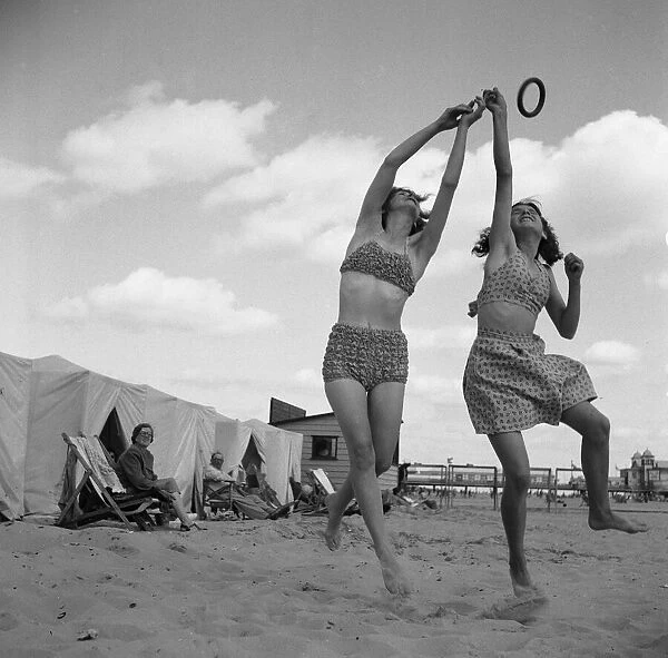 Holidaymakers playing with a quoit on the beach close to the Britannia Pier