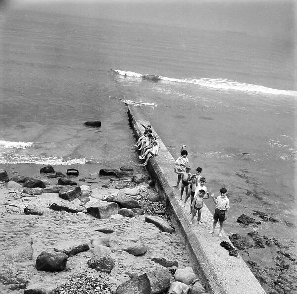 Holidaymakers on a sewerage pipe on the beach at Tynemouth near Newcastle Upon Tyne