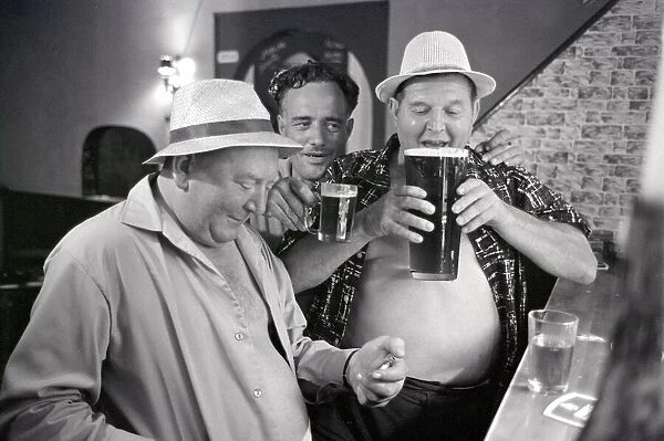 Holidays Spain Spanish Holiday three fat men drinking beer at a bar. June 1965