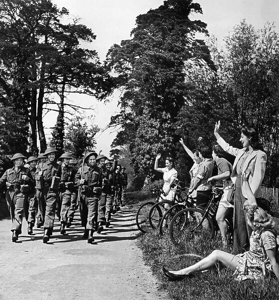 Home Guard volunteers are cheered by local residents sitting on the side of the road as