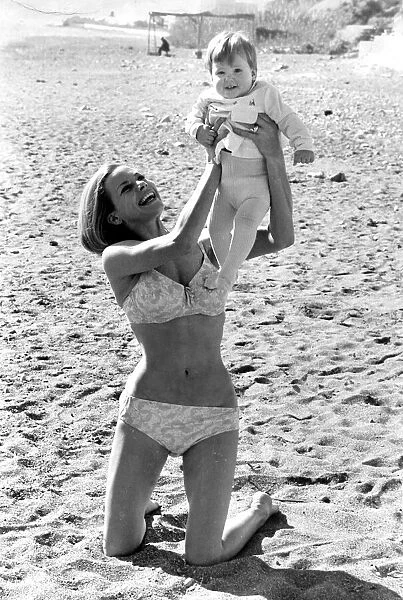 Honor Blackman wearing biini playing with daugher Lottie on beach in Spain during filming