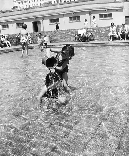 Hot weather scenes in Margate, Kent. Two young children playing in a paddling pool