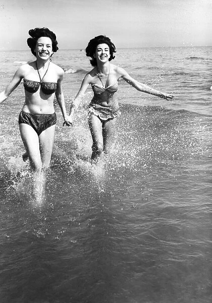 Hot weather scenes in Margate, Kent. Two young women running in the sea. 30th June 1961