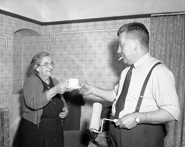 House wife hands her husband a cup of tea whilst he takes a break from the painting