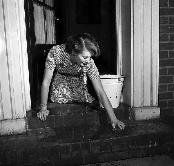 House wife seen here scrubbing the front door step. Circa 1952
