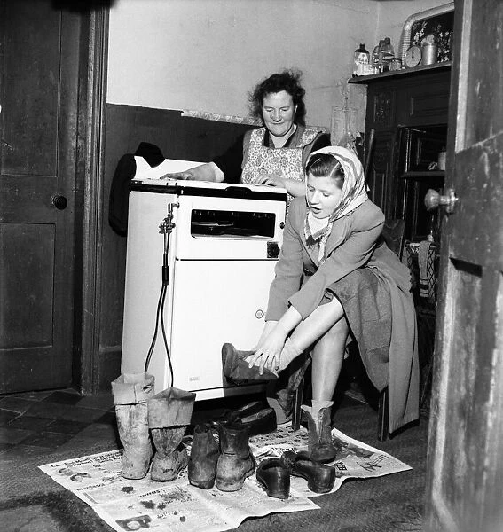 Housewife Mrs. Gladys Coates changes into better footwear after leaving the the mud
