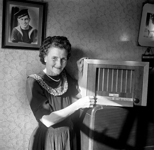 A housewife tunes in her wireless set to The BBC home service. Circa 1953 D6046