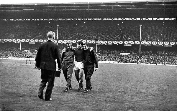 Howard Kendall, back in the Everton team after injury, is helped off the pitch after only