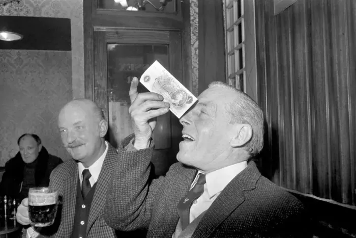 Framed Print : Humour / Unusual. John Mitchell balancing a pound note. February 1975 75-00662-002 Framed Print : Humour / Unusual. John Mitchell balancing a pound note. February 1975 75-00662-002