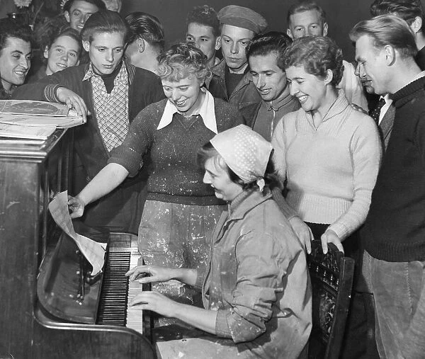 Hungarian Refugees Refugees sing around a piano in a great common room