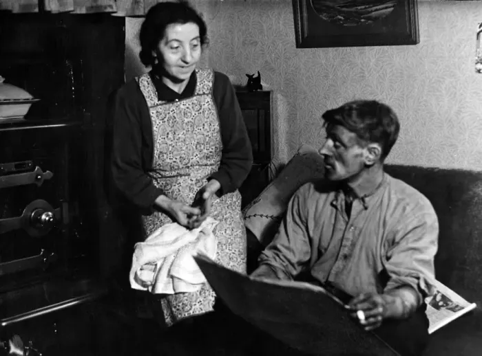 Framed Print : Husband Tom, home from the pit, likes a look at the paper as his wife waits to dish up