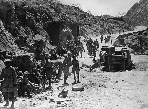Indian army soldiers at a junction of roads where an Italian lorry can be seen blown