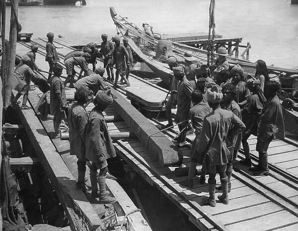 Indian troops under the direction of British officers unload a barge on the Tigris River
