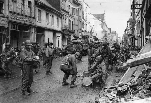 Infantry of the US 9th Army pass a chow-line in the streets of Neuss