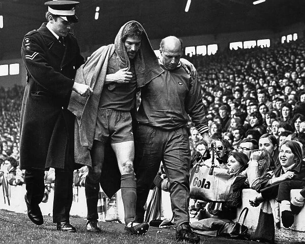 Injured Liverpool footballer Steve Heighway is helped off the pitch by trainer Ronnie