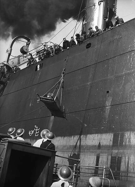 Injury merchant sailor being winched down to a launch during the Second World War